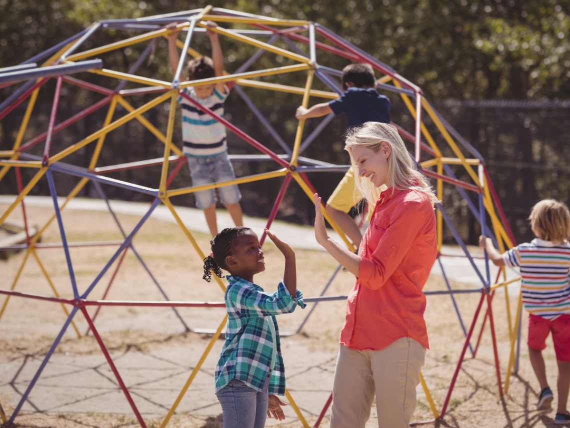 a grown up supervising children as they play on a climbing dome.jpg
